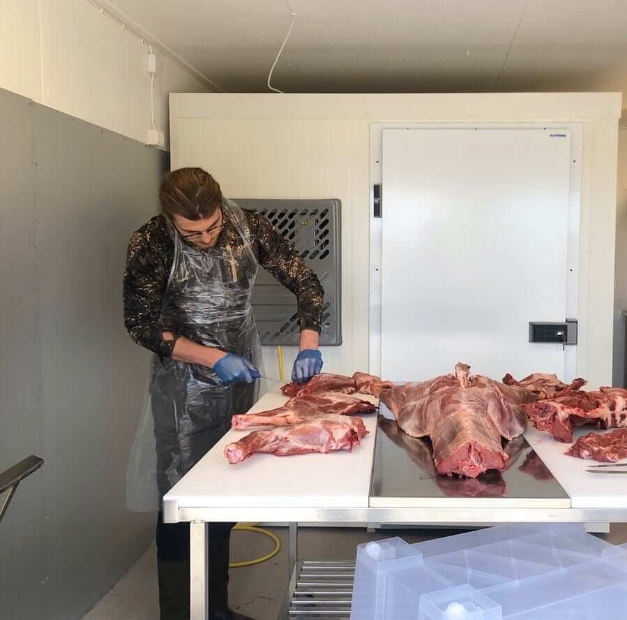 Adrian står och styckar till köttbitar i slakteriet, av sitt tidigare fällda vildsvin